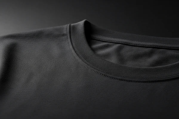 Close-up of a black crew-neck t-shirt showing the ribbed collar and fine fabric texture against a dark background.